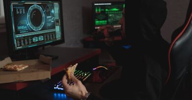 Man in Black Hoodie Eating His Snack in Front of the Computer