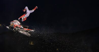 man in red jacket and white pants riding on red and white snowboard during nighttime