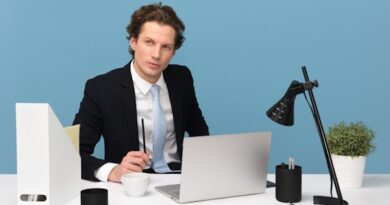 man sitting on chair beside laptop computer and teacup