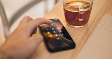 A person holding a cell phone next to a cup of coffee