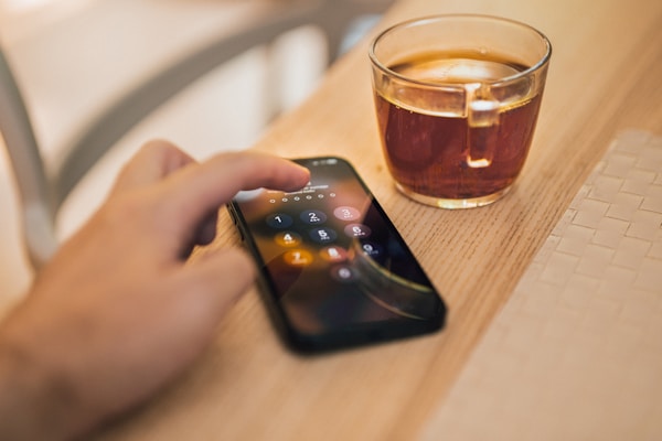 A person holding a cell phone next to a cup of coffee